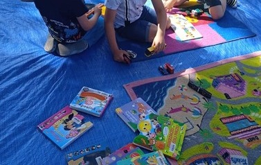 Dzieci bawią się samochodzikami i czytają książki